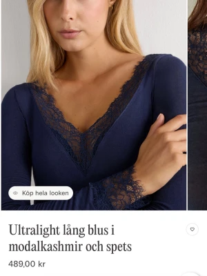 Mörkblå spetsblus i modalkashmir - Supersnygg mörkblå blus med lång ärm i ultralätt modalkashmir och spetsdetaljer vid v-ringning och ärmslut. 