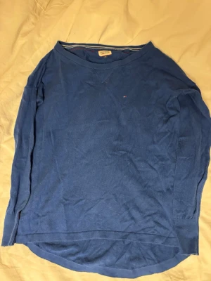 Blå långärmad tröja Tommy Hilfiger - En enkel blå långärmad tröja från Tommy Hilfiger med rund halsringning och liten logga på bröstet. Tröjan har ribbade muddar vid ärmslut och nederkant samt en avslappnad passform. Perfekt för en chill och stilren look.