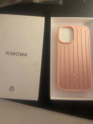 Rimowa mobilskal   - Snyggt rosa mobilskal från Rimowa med klassisk räfflad design och diskret logga. Skalets material känns robust och ger ett exklusivt intryck. Passar perfekt för dig som vill ha ett stilrent och trendigt skydd till din mobil. Modell iPhone 17