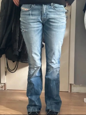 Blå jeans från Diesel med slitningar - Säljer ett par blå lågmidjade jeans från Diesel med snygga slitningar på framsidan. I mycke bra skick bortsett från små slitningar längst ner (se sista bilden) men de går att fixa till om man klipper bort trådarna🙌