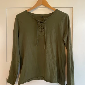  långärmad tröja med snörning - Säljer en khaki långärmad t shirt med snygg snörningsdetalj fram🫶