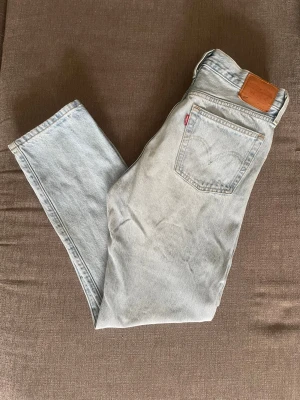 Levi's ljusblå raka jeans - Säljer ett par klassiska ljusblå Levi's jeans med raka ben och hög midja. Jeansen har fem fickor, läderpatch bak och den ikoniska röda Levi's-taggen på bakfickan. Tillverkade i slitstark denim, perfekta för en avslappnad och tidlös look. Använda men i fint skick.