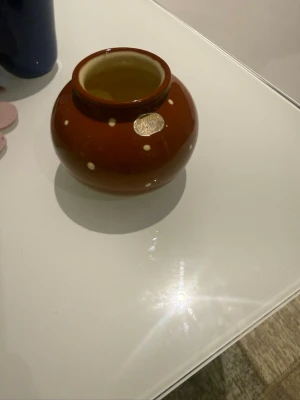 Brun prickig keramikskål Nittsjö - Säljer en rund brun keramikskål från Nittsjö med vita prickar och märkning undertill. Skålen har en bred öppning och klassisk retrostil, perfekt som dekoration eller förvaring av småsaker.