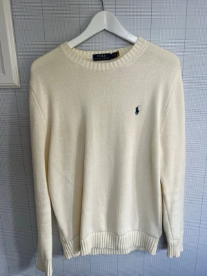 Vit stickad tröja från Polo Ralph Lauren - Nästan aldrig använd, skitsnygg och klassisk Ralph lauren stickad tröja. Tröjan är perfekt nu inför sommar då den är en riktigt härlig färg. 