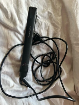 Svart plattång från GA.MA Ceramic - Plattång från GA.MA med keramiska plattor och svart slimmad design. Utrustad med strömbrytare och lång sladd för enkel användning. Perfekt för att styla och räta ut håret snabbt och smidigt.