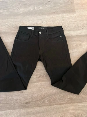 Svarta Replay jeans - Snygga svarta jeans från Replay med klassisk femficksmodell och smal passform. Jeansen har svarta sömmar, bälteshällor och en diskret logga på fickan. Tillverkade i stretchigt material för extra komfort.