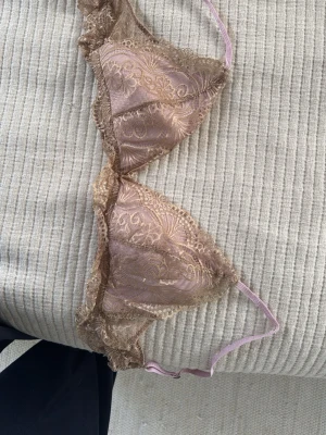 Rosa spets-bh med blommönster - Säljer en söt trekants-bh i ljusrosa med beige spetsdetaljer och blommigt mönster. Kommer ej till användning då den är för stor. S/M