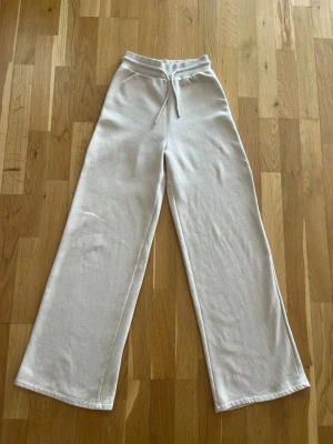 Vida ljusgrå mjukisbyxor med dragsko - Säljer ett par jättefina mjukisbyxor i beige med breda, raka ben och medelhög midja💕 Säljer för 250!
