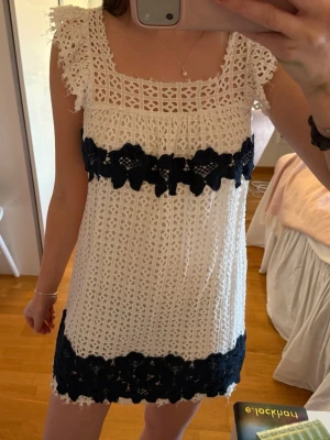 Vit spetsklänning med svarta detaljer - Säljer en söt vit klänning i spets med breda svarta spetsband över byst och nederkant. Klänningen har fyrkantig ringning, volangärmar och är fodrad. Fint skick! Storlek 38 men är mer som 36 skulle jag säga❤️