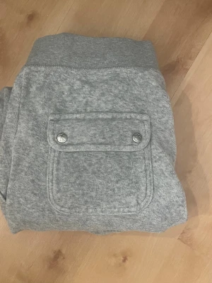 Gråa Juicy Couture byxor - Säljer ett par grå Juicy Couture byxor gjorda i mjukt, bekvämt material. Perfekta för dagar när du vill vara extra comfy.