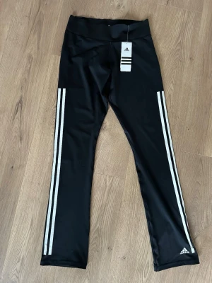 Svarta leggings med vita ränder Adidas - Superfina svarta Yoga pants/leggings  från Adidas Sitter tajt uppe vid låren och utsvängda nere vid benen. Aldrig använda och prislapp sitter kvar