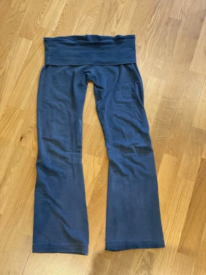 Blå yoga pants - Säljer ett par mörkblå leggings med bootcut-ben och bred linning i midjan. Sköna och stretchiga, perfekta för en avslappnad stil. Materialet känns mjukt och följsamt. Inget synligt märke.