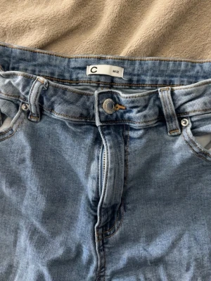 Ljusblå bootcut jeans från Cubus - Säljer ett par ljusblå jeans från Cunus i bootcut modell med klassisk femficksdesign och dragkedjegylf. Jeansen har bälteshällor och kontrastsömmar. Perfekta till en avslappnad look och passar till det mesta.