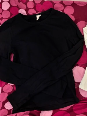 Svart och vit långärmad topp - Två basic långärmade toppar i svart och vitt. Båda har rund halsringning och är tillverkade i mjukt bomullstyg. Du får båda för priset.