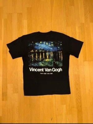 Svart Vincent Van Gogh t-shirt - Cool svart t-shirt med tryck av Van Goghs konstverk 'Starry Night' på ryggen och texten 'Vincent Van Gogh' både fram och bak. T-shirten har klassisk passform och korta ärmar. Perfekt för dig som gillar konst och vill sticka ut.