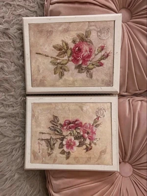 Två tavlor med blommotiv - Säljer två tocka tavlor med blommotiv i rosa och grönt. Tavlorna har vita träramar och motiv av rosor och andra blommor på beige bakgrund med vintagekänsla. Perfekta som dekoration i sovrum eller vardagsrum.