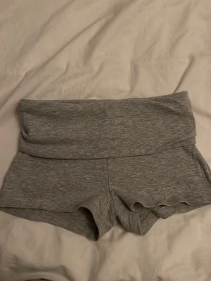Grå höga shorts i bomull - Mysiga grå shorts med hög midja och bred linning. Tillverkade i mjukt bomullsmaterial, perfekta för avslappnade dagar eller träning. Klassisk och enkel design utan synliga detaljer.