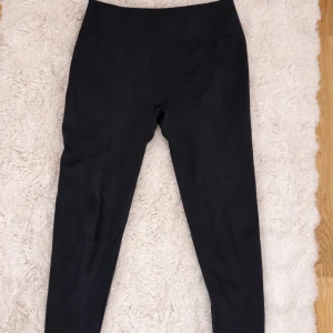 Svarta leggings från Relode - Säljer ett par gråa leggings från Relode med hög midja och scrunch-detalj bak. De är tighta och stretchiga, perfekta för träning. Materialet känns mjukt och följsamt. Relode-logga i midjan bak. 