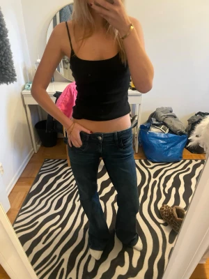 Mörkblå bootcut jeans - Använt 1 gång. Säljer ett par mörkblå bootcut jeans med låg midja och klassisk femficksdesign. Jeansen har en avslappnad passform och är tillverkade i denim med lätt stretch. Perfekta för dig som gillar en retro och bekväm stil.