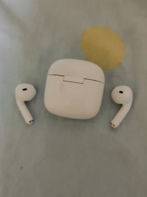 Trådlösa vita in-ear hörlurar - Säljer ett par trådlösa vita in-ear hörlurar med tillhörande laddningsetui. Hörlurarna har en stilren och minimalistisk design med rundade kanter och passar perfekt för musik, poddar eller för och scrolla.. Laddningsetuiet är kompakt och lätt att ta med sig.