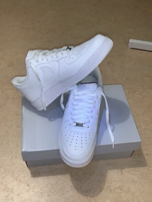 44,5 nya Nike Airforce 01 vit - Säljer för att behövde Nike Airforce 01 akut i butik fanns det bara 44,5 jag har 45,5 så köpte dom endå oavsett dom va 1 storlek mindre sen testa så va det ingen skön känsla orkade inte gå tillbaka och lämna dom för bor långt ifrån butiken en sko med skön mjuk Shoe crease mjuk kan kännas som 44 med Shoe crease för uttrymet minskas med crease. Skorna har perforerad tå, vita skosnören och material i läder. Perfekta för en clean och stilren look. Passar till det mesta och är ett måste i garderoben.