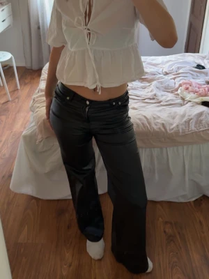 Svarta vida jeans i skinnimitation - Säljer ett par svart byxor som har midwaist. Aldrig använt, som helt nya. 