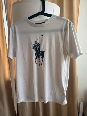 Vit t-shirt Polo Ralph Lauren - Snygg vit t-shirt Polo Ralph Lauren. Klassisk rund halsringning och korta ärmar. Perfekt till jeans eller shorts för en clean och stilren look.