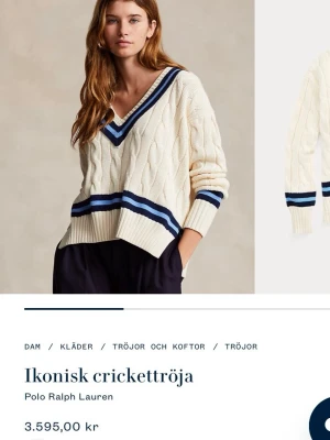 Vit crickettröja Polo Ralph Lauren - Kabelstickad crickettröja i offwhite från Polo Ralph Lauren med djup V-ringning och blå samt mörkblå ränder vid hals, ärmslut och midja. Oversized passform och ribbade muddar ger en sportig och klassisk look.