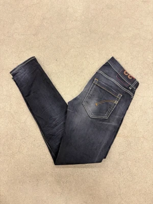 Mörkblå slim fit Dondup jeans, Dondup George - Snygga Dondup mörkblå slim fit jeans med klassiska fem fickor och kontrastsömmar. Jeansen har en smal passform och är tillverkade i ett stretchigt denimtyg som ger en bekväm känsla. Perfekta för en trendig och avslappnad look. Storlek 32.