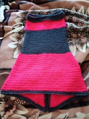 Virkad dra på kjol  röd och svart glittrig stlX XXS , midjemått 35 cm bred. - Unik virkad dra på kjol vida breda blockränder av röd  och svart. ar en lätt  utsvängd form med sprung nedtill kjolen i storleken XXXS och av materialet Akrylgarn samt polyester. Går  att variera vilken sida man vill ha fram eller bak.