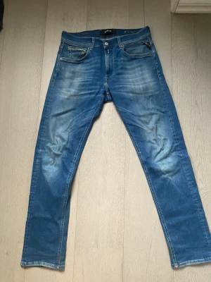 Blå Replay Hyperflex jeans - Snygga blå jeans från Replay Hyperflex med klassisk femficksmodell och stretchigt material. Jeansen har en tvättad look med ljusa partier och raka ben. Perfekta för dig som vill ha både stil och komfort.