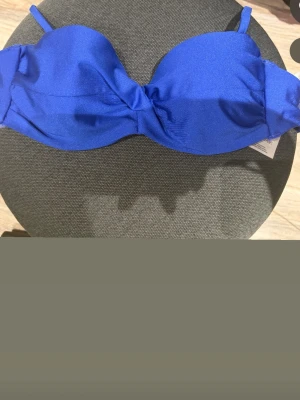 Blå bikiniöverdel med twist framtill - Oanvänd bikiniöverdel från h&m med prislappen på, stl 75A.
