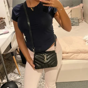 Svart quiltad axelväska från YSL - Säljer en svart quiltad axelväska från YSL med silverfärgad logga framtill. Väskan har justerbar axelrem och stilren design i skinn. Perfekt för dig som vill ha en snygg och klassisk väska med lyxig känsla. Den är köpt nyligen här på plick men aldrig kommit till användning 💕