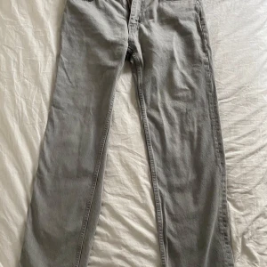 Grå jeans från Gina Tricot, strl 38 - Snygga grå jeans från Gina Tricot, modell Perfect Jeans. De har klassisk femficksdesign, raka ben och normal passform. Materialet är mjukt och bekvämt, perfekt för dig som gillar stilrena och enkla jeans. Färgen är ljusgrå och passar till allt.