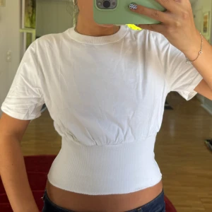 Vit croppad topp med ribbad midja - Vit T-shirt med ribbad midja. Korsett aktig 