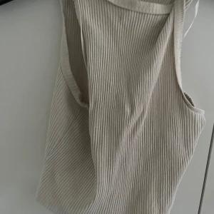 Ribbade ärmlösa linnetoppar i 3 färger - Tre ribbade linnetoppar i vit, svart och mörkgrön. Alla är ärmlösa med breda axelband och rund halsringning. Materialet är stretchigt och har en tydlig ribbad struktur som ger en cool och avslappnad vibe. Perfekta att styla med jeans eller shorts. Alla är i samma storlek.