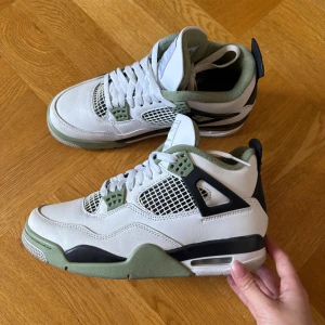 Nike Air Jordan 4 i sea foam  - Nike Air Jordan 4 sneakers i vitt skinn med detaljer i olivgrönt och svart. Färgen på dessa skor heter Sea foam om jag minns rätt. Skorna har tecken på användning men går att göra rent. St 38 men passar mig som har 37 också. 99% säker att att boxen finns här hemma, är det viktigt för dig som köper letar jag självklart rätt på den! Skriv vid funderingar🩷