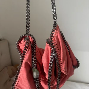Rosa axelväska Stella McCartney - Säljer en snygg rosa axelväska från Stella McCartney med silverfärgade band. . Perfekt storlek för det viktigaste. Kan mötas upp i Stockholm 