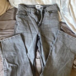 Grå jeans med slits från 157 Split - Snygga grå jeans från 157 Split med raka ben och cool slits nertill. Klassisk femficksmodell och normal passform. Perfekta för dig som vill ha en chill och trendig look. Jeansen är i ett mjukt denimtyg och har en stilren, ljusgrå tvätt. Helt nya