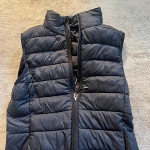 Svart dunväst med dragkedja - Säljer en svart ny ridväst från CRW, köpt strax innan sommaren och använd cirka en gång. Kan användas till att rida eller bara ha en snygg väst över en tjocktröja i stallet. Storlek XS men passar S också.