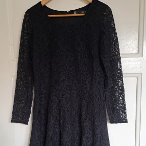 Svart spetsklänning från Prêt - Supersnygg svart klänning från Prêt i spets med långärmade ärmar och rund halsringning. Klänningen är kort och har ett feminint, figurnära snitt med vacker spets över hela plagget. Perfekt för dig som vill sticka ut med en klassisk look.