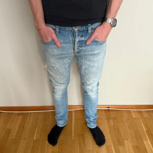 Nudie grim Tim - Trendigaste jeansen just nu! Säljer dessa snygga Nudie grin Tim med slitningar. Jeansen är i bra skick, dock är fickan lite trasig på insidan, inget som påverkar funktionaliteten och det går enkelt att sy ihop för den händige. Modellen är 186 cm lång. 