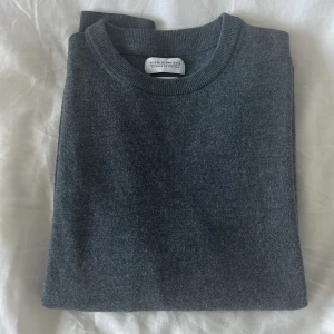 Grå merinotröja These Glory Days - Snygg mörkgrå rundhalsad tröja från These Glory Days i mjuk och lyxig merinoull. Klassisk passform med ribbade muddar vid ärmslut och nederkant. Perfekt för dig som gillar stilrena och enkla plagg med premiumkänsla.