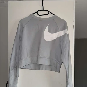 Ljusgrå croppad sweatshirt från Nike - Säljer en ljusgrå croppad sweatshirt från Nike med stor vit logga på på sidan.