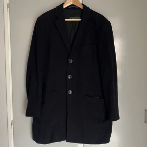 Svart rock från Esprit Large - Klassisk svart rock från Esprit, storlek Large med tre knappar framtill och två fickor med lock. Jackan har en stilren krage och är helfodrad för extra komfort. Fodret i båda fickorna är trasigt, syns enkelt ihop av kunnig. Obehandlad fläck syns på sista bilden. 