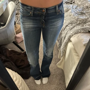 Lågmidjade jeans  - Lågmidjade jeans som är uppsprättade där nere. St 27/32,, midjemåttet tvärs över: ca 36 cm, innerbenslängden: ca 85 cm
