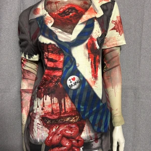 Halloween t-shirt med zombie-tryck S - Säljer en unik t-shirt med realistiskt zombie- och blodtryck, komplett med tryckt slips och skjorta. Perfekt för halloween eller temafest! Långärmad T-shirt. Helt ny. Storlek S. Material i lite stretchig polyester.
