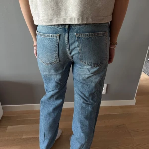 Blå raka jeansbyxor - Klassiska blå jeansbyxor med raka ben och normal passform. Byxorna har bälteshällor och stängs med dragkedja och knapp. Perfekta till vardags för en avslappnad stil.