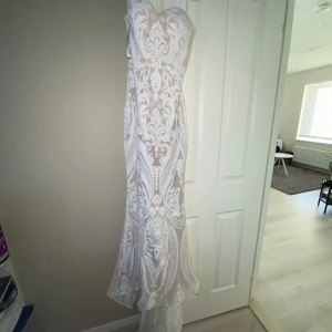 Vit långklänning med spetsmönster från Tina Holly !PRISET KAN DISKUTERAS! - !PRISET KAN ALLTID DISKUTERAS! Säljer en elegant vit långklänning från Tina Holly med vackert spetsmönster och figurnära passform. Klänningen är axelbandslös och har en transparent look med nude underklänning. Perfekt för speciella tillfällen, klänningen har paljetter och ett vackert släp❤️(använd en gång 2022)