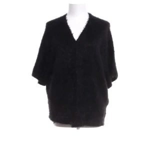 Svart pälsjacka med v-ringning - Mysig svart lurvig kofta med v-ringad hals och lös passform. Jackan har trekvartsärmar och är perfekt för dig som vill ha en stilren och fluffig look. Enkel att matcha med olika outfits och ger en lyxig känsla.